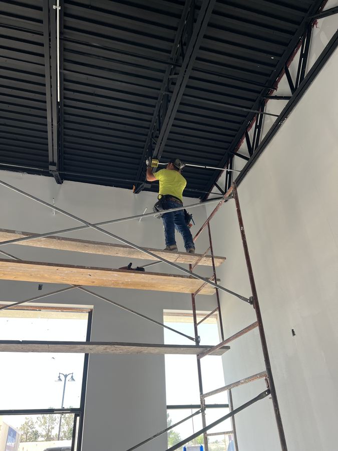 Onetime Electrical electrician working overhead from scaffolding on a commercial build-out
