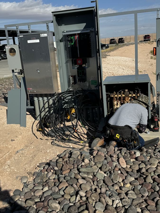 Electrician terminating feeder conductors inside pad mounted service gear on site