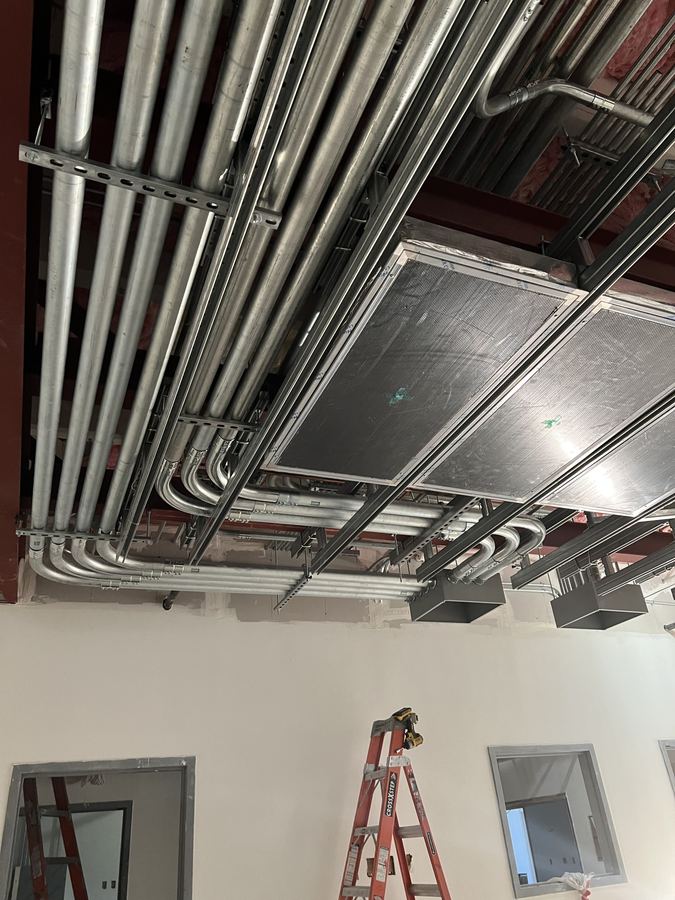 Racked conduit runs and strut supports above a commercial ceiling